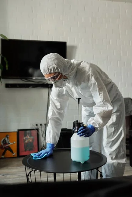 services-02 A worker in protective gear disinfects a kitchen, ensuring a clean and safe environment.